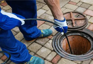 Rohrreinigung am Kanaldeckel mit Spirale durch Techniker